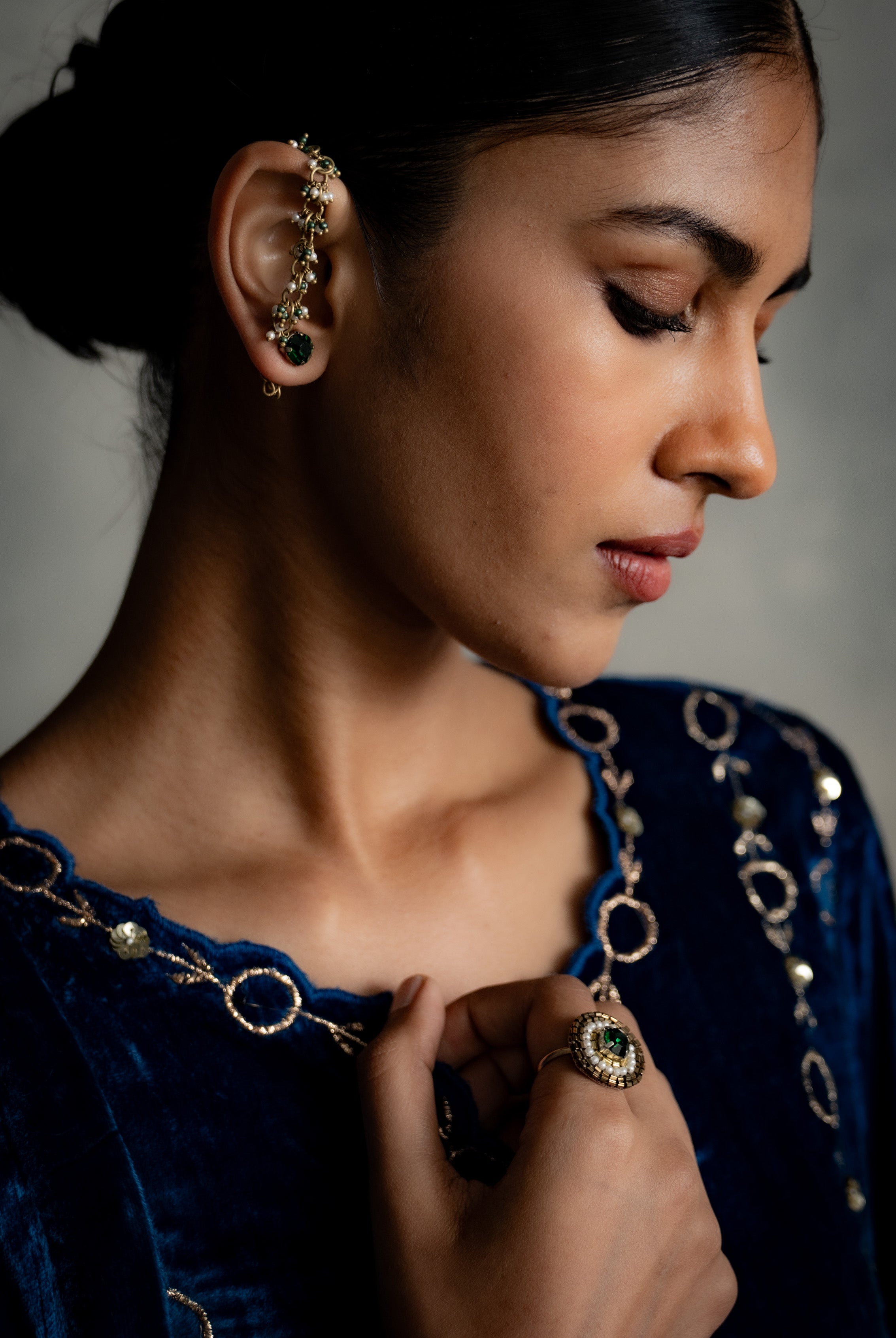Woman wearing gold earrings and a necklace with a dark background