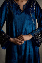 Blue dress with intricate detailing on sleeves and neckline against a neutral background